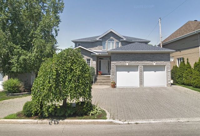 Une grande maison avec deux garages et une allée