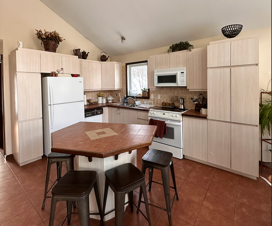 Une cuisine avec une table et des tabourets et un réfrigérateur