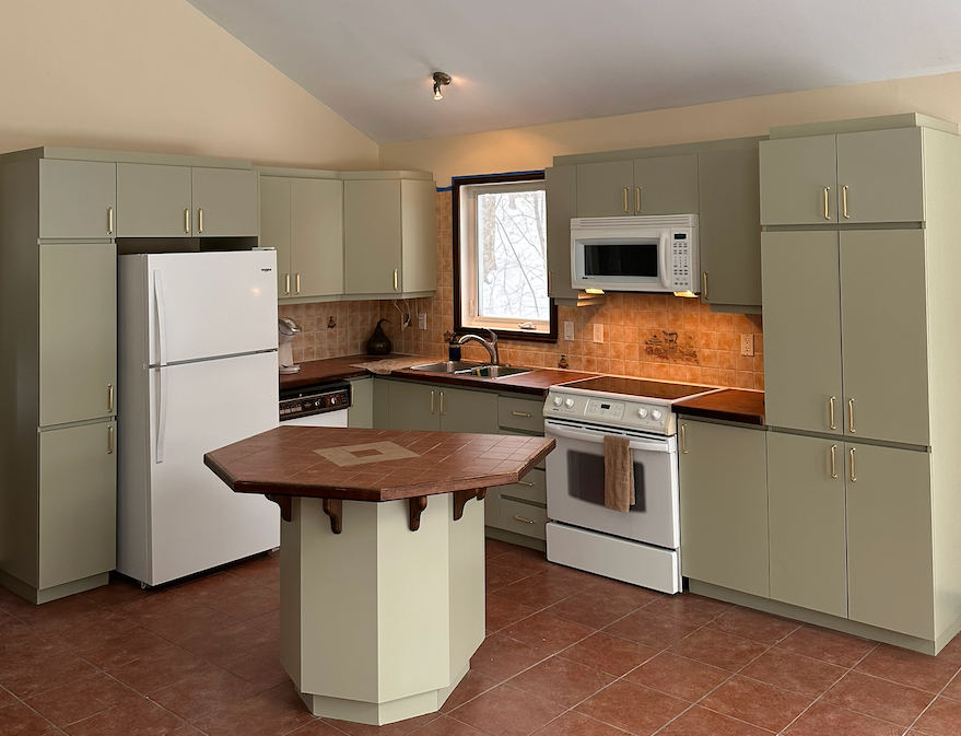 A kitchen with a stove a refrigerator and a microwave