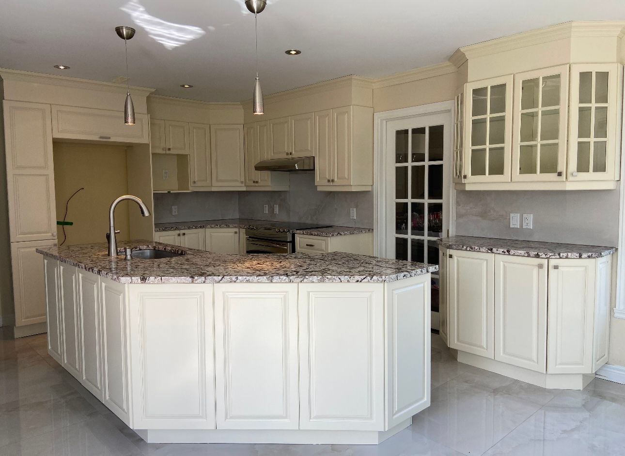 Une cuisine avec des armoires blanches et des comptoirs en granit.