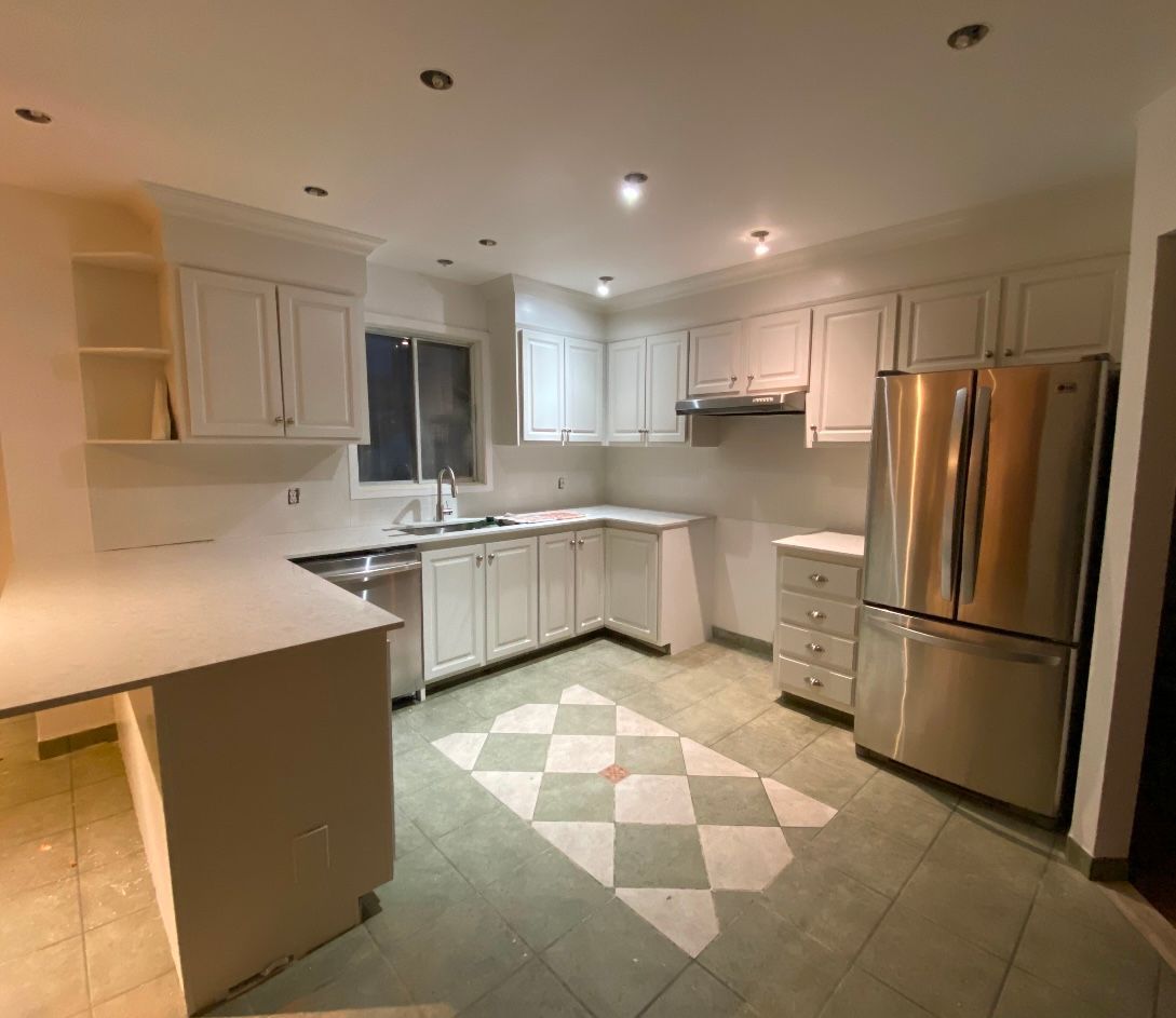 Une cuisine avec des armoires blanches et un réfrigérateur en acier inoxydable.