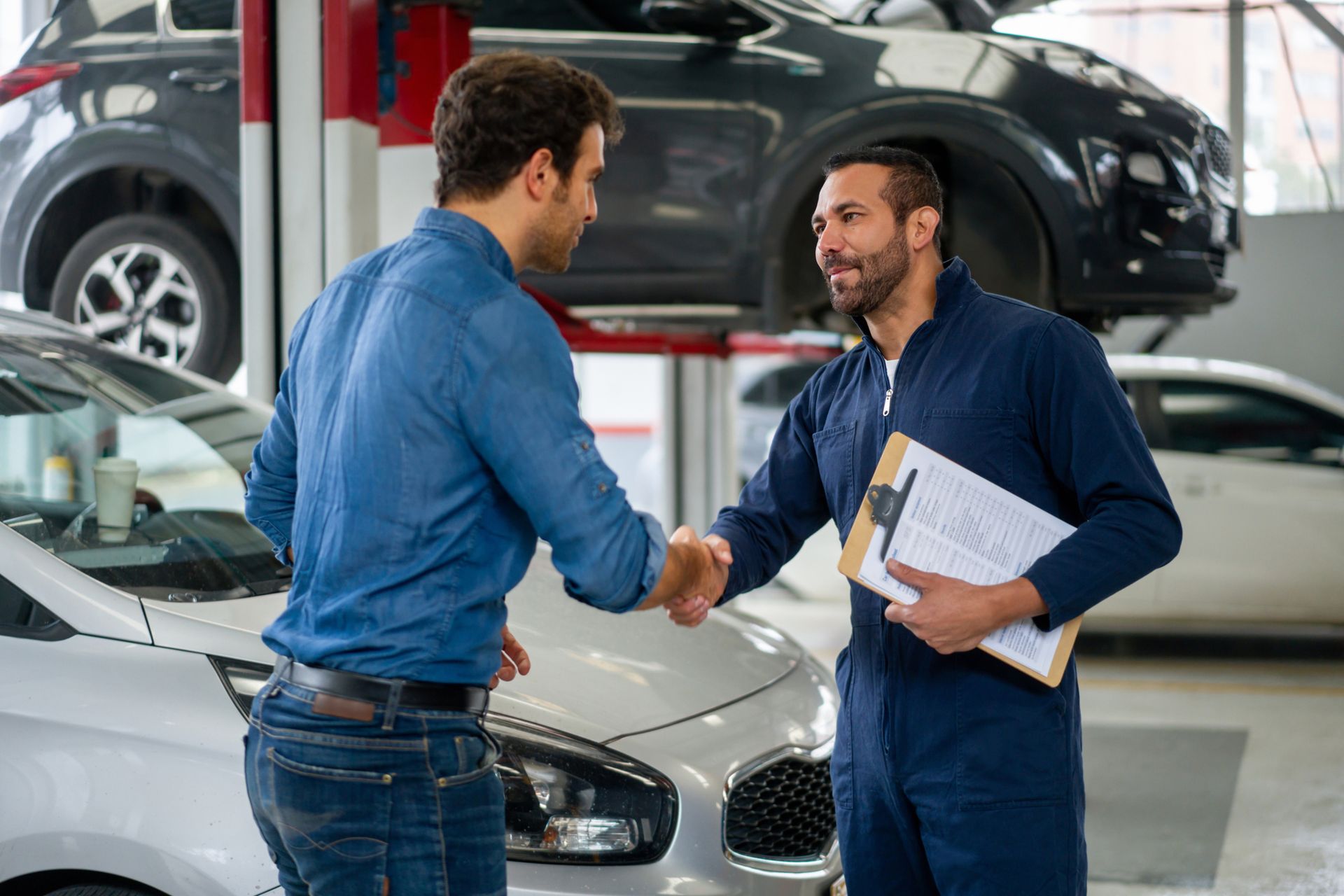 A man is shaking hands with a mechanic in a garage.