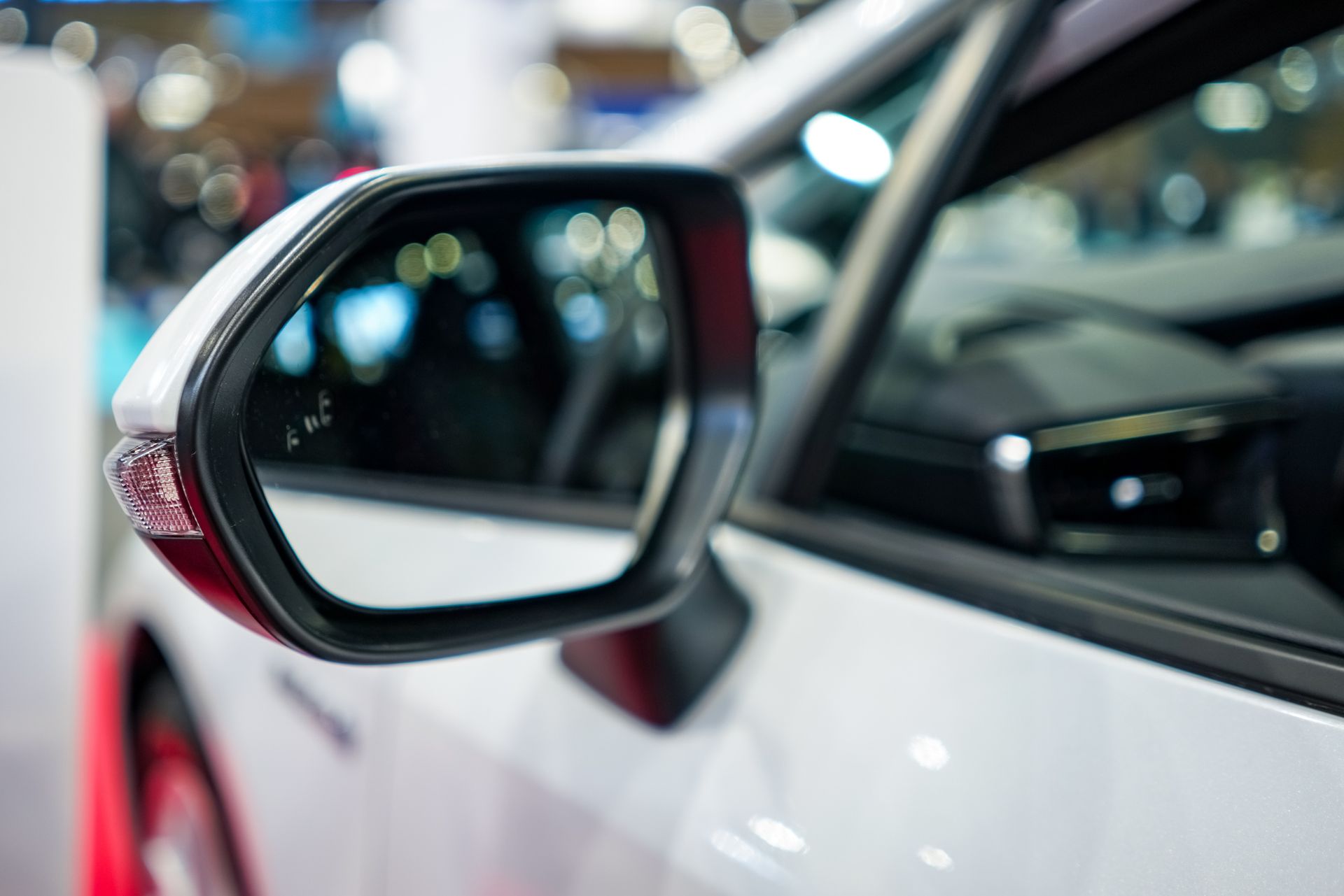 A close up of a side view mirror on a white car.