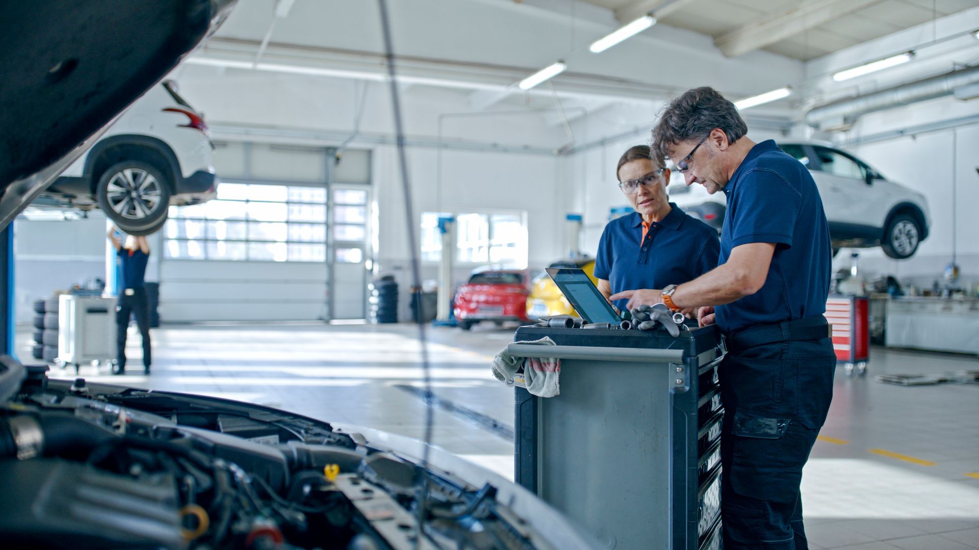 Two mechanics are working on a car in a garage.