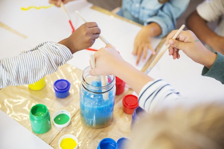 Litltle boy playing with coloured shapes on a red table