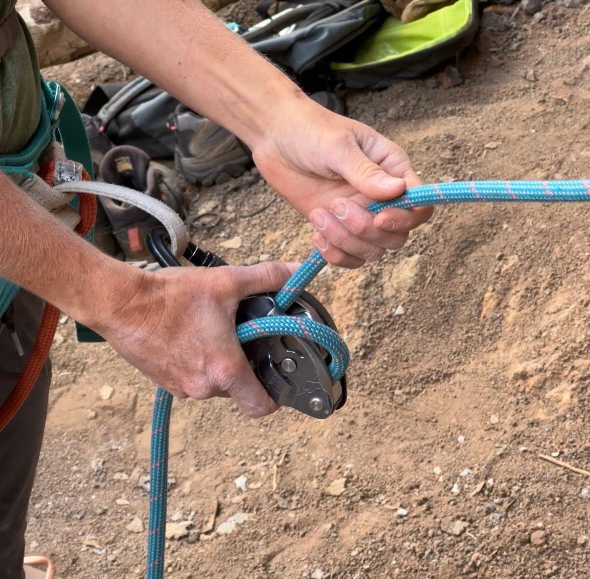 Hands holding a climbing rope and belay device