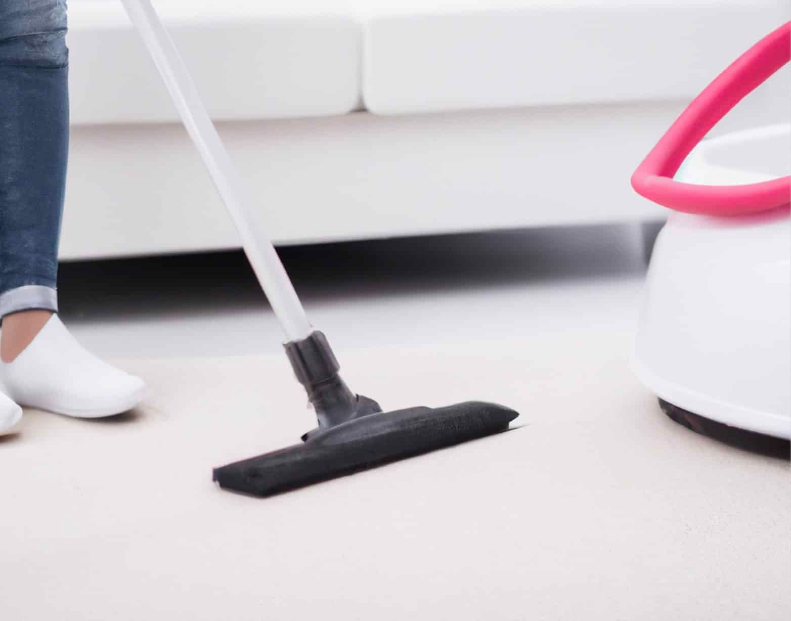A person wearing green gloves is using a vacuum cleaner to clean a carpet.
