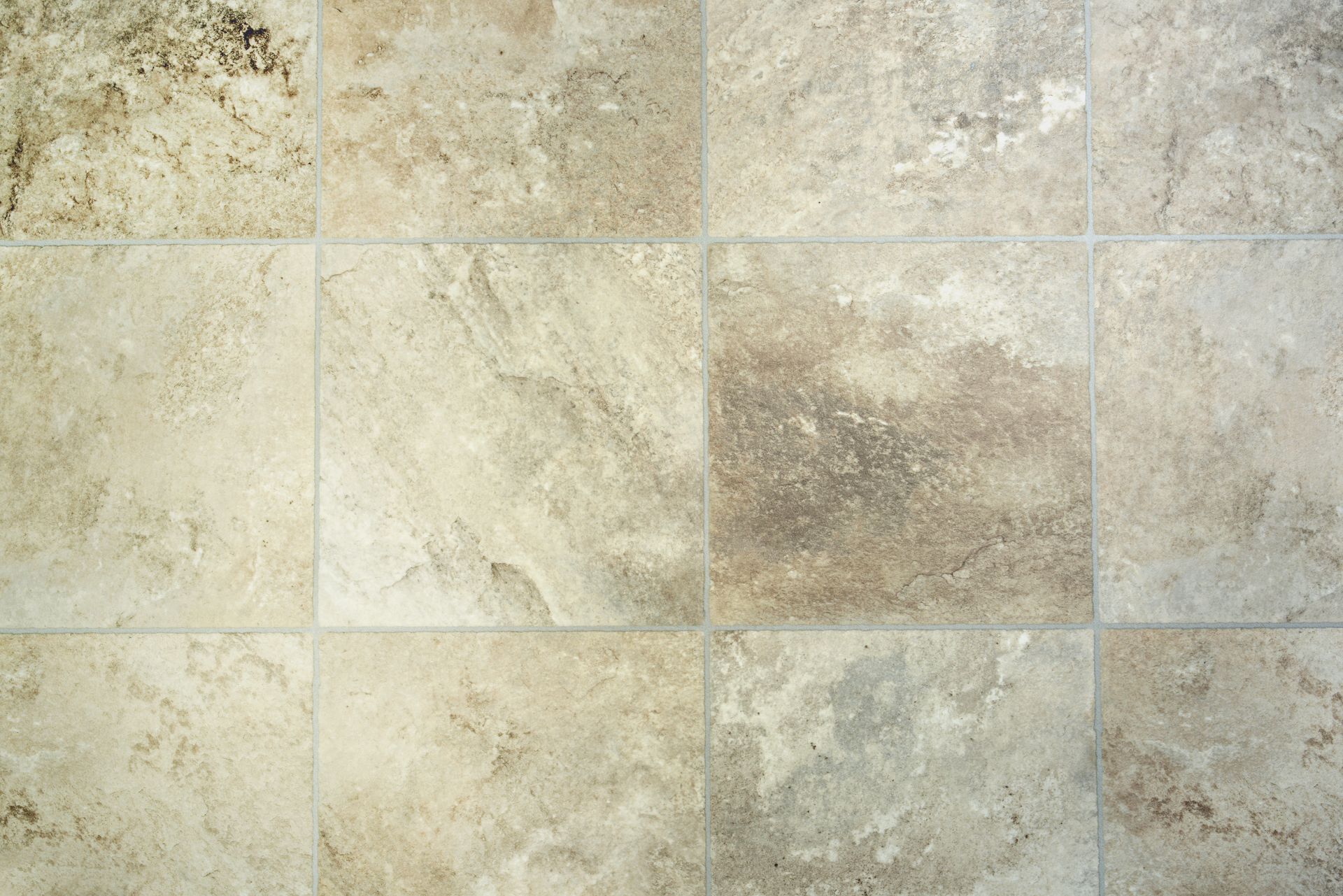 Person installing wooden flooring, bending a piece into place over a light beige adhesive layer.