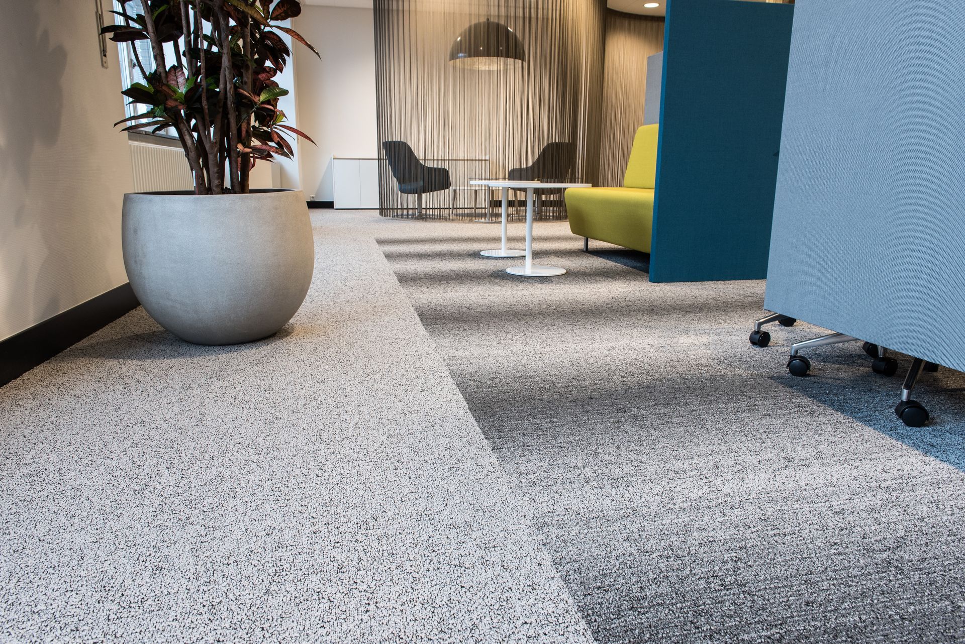 Office lobby with speckled flooring, potted plant, and seating area.