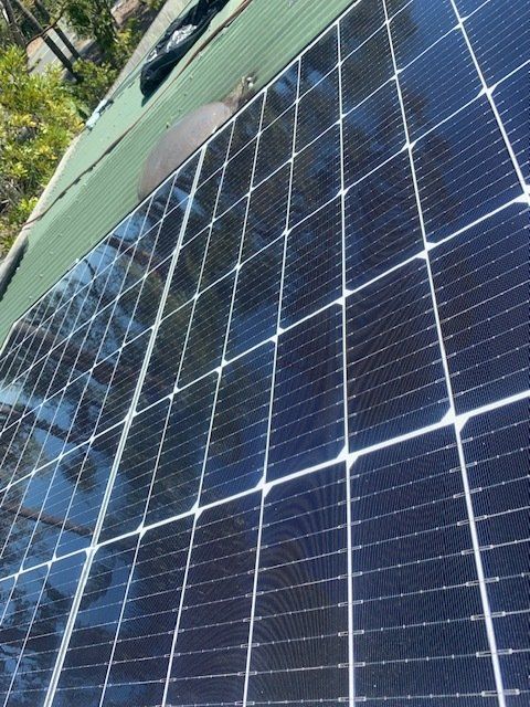 Solar panels on a green roof, reflecting a bright sky.