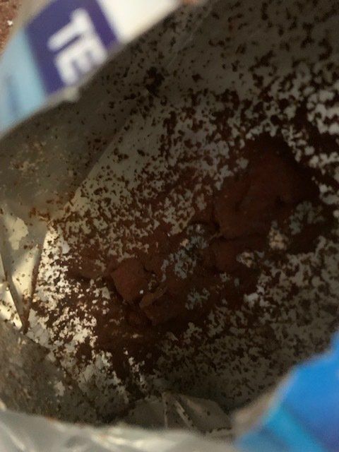 Inside an opened packet, brown powder surrounds a solid, reddish-brown clump.