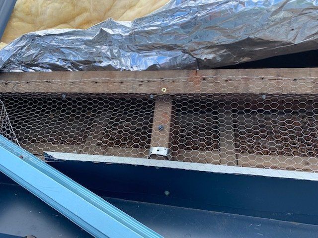 Close-up of a gutter with wire mesh and a metal support, likely for preventing debris.