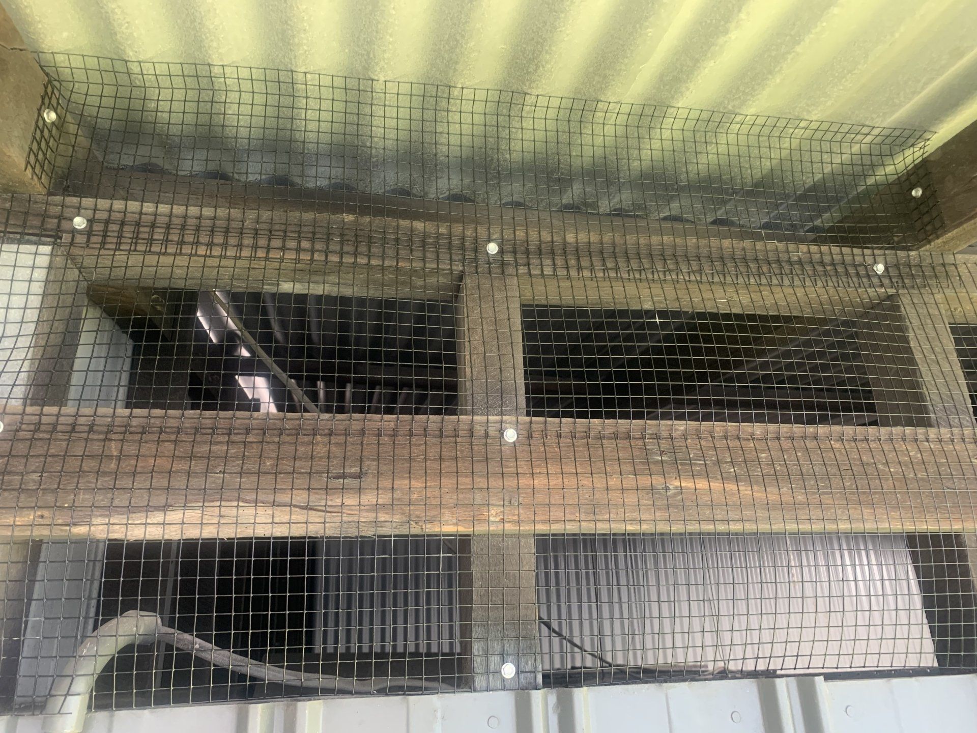 Wire mesh covering wooden beams and openings in a structure.