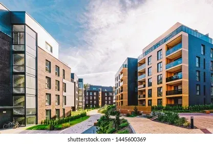 Modern apartment buildings with brick and dark blue facades under a cloudy sky.