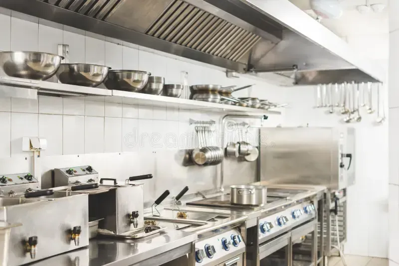 Commercial kitchen with stainless steel appliances and cookware.