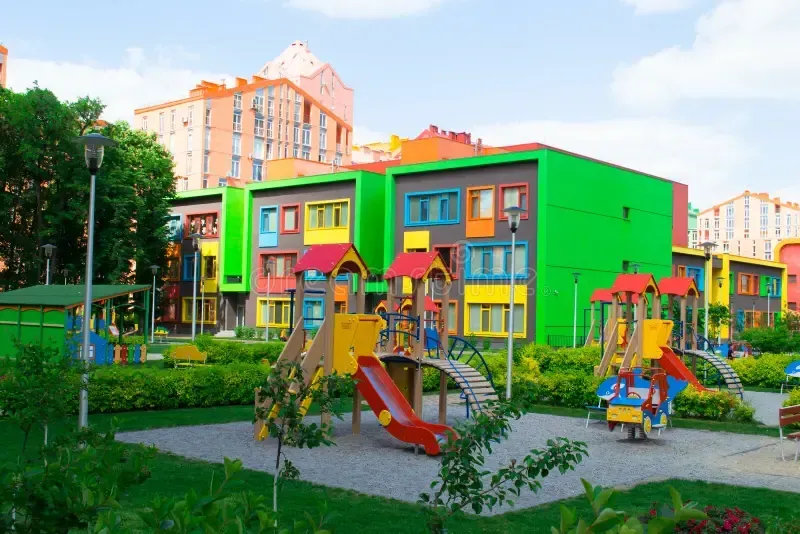 Colorful playground with slides, climbing structures, and a vibrant building in the background.