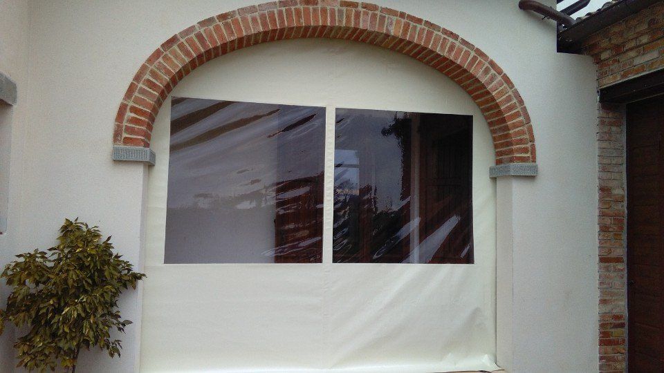 Una finestra bianca con un arco in mattoni e una pianta davanti