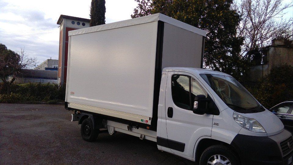 Un furgone bianco è parcheggiato in un parcheggio accanto a un edificio.