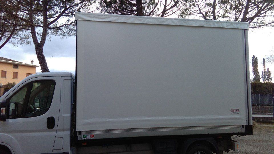 Un camion bianco è parcheggiato in un parcheggio con alberi sullo sfondo.
