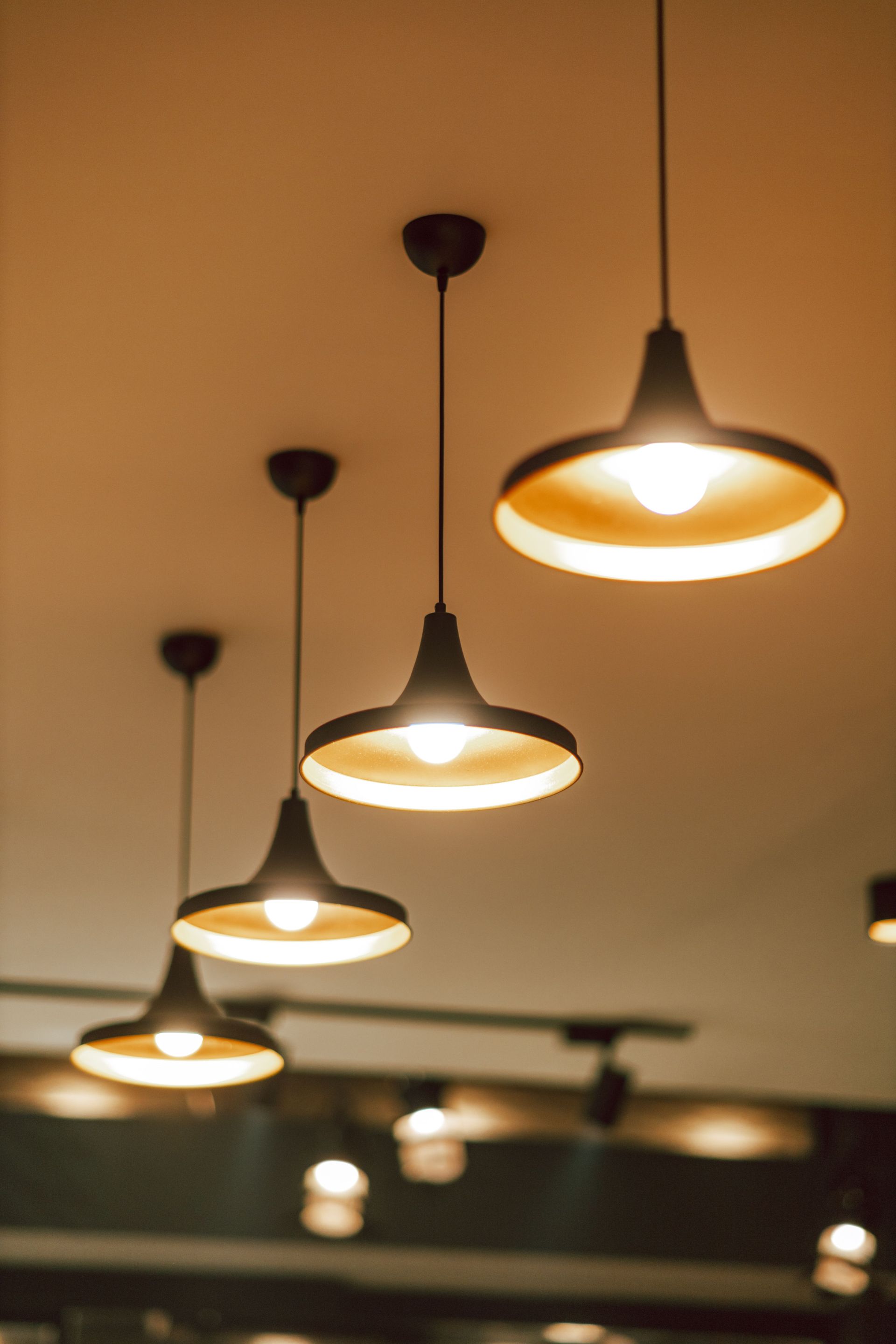 Row of warm pendant lights hanging from a ceiling in a softly lit interior