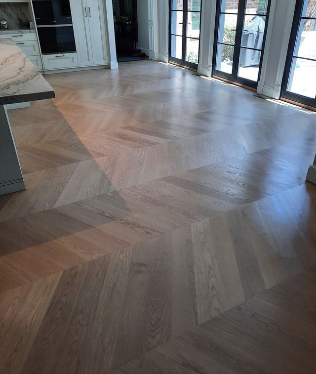 A wooden floor with a herringbone pattern in a kitchen.