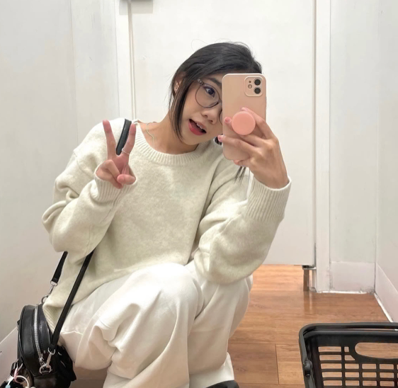 Woman with long black braids smiling, looking at the camera against a green background.