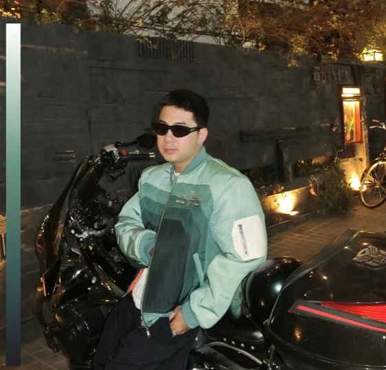 Woman with curly blonde hair smiles at the camera, wearing a black shirt against a yellow background.