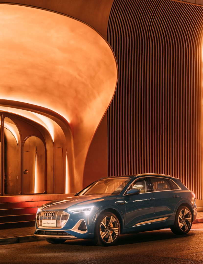 Blue Audi SUV parked in front of a modern, orange-lit building.