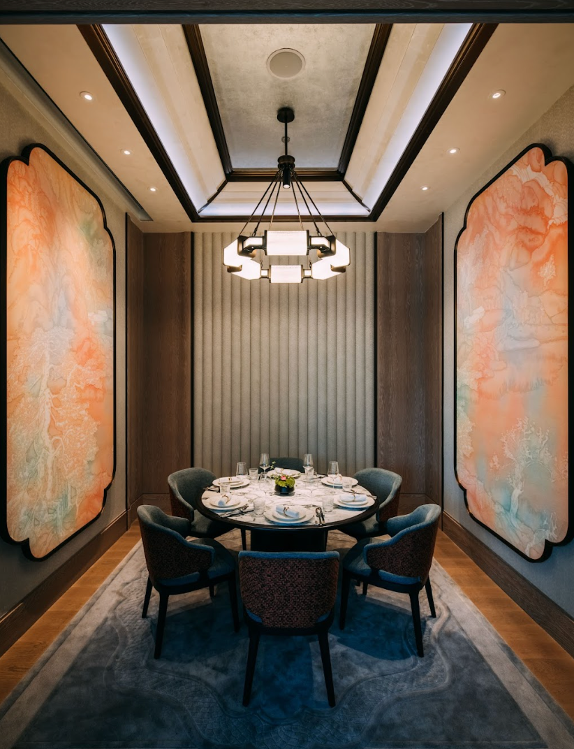 Elegant dining room with round table, six chairs, artwork on walls, chandelier.