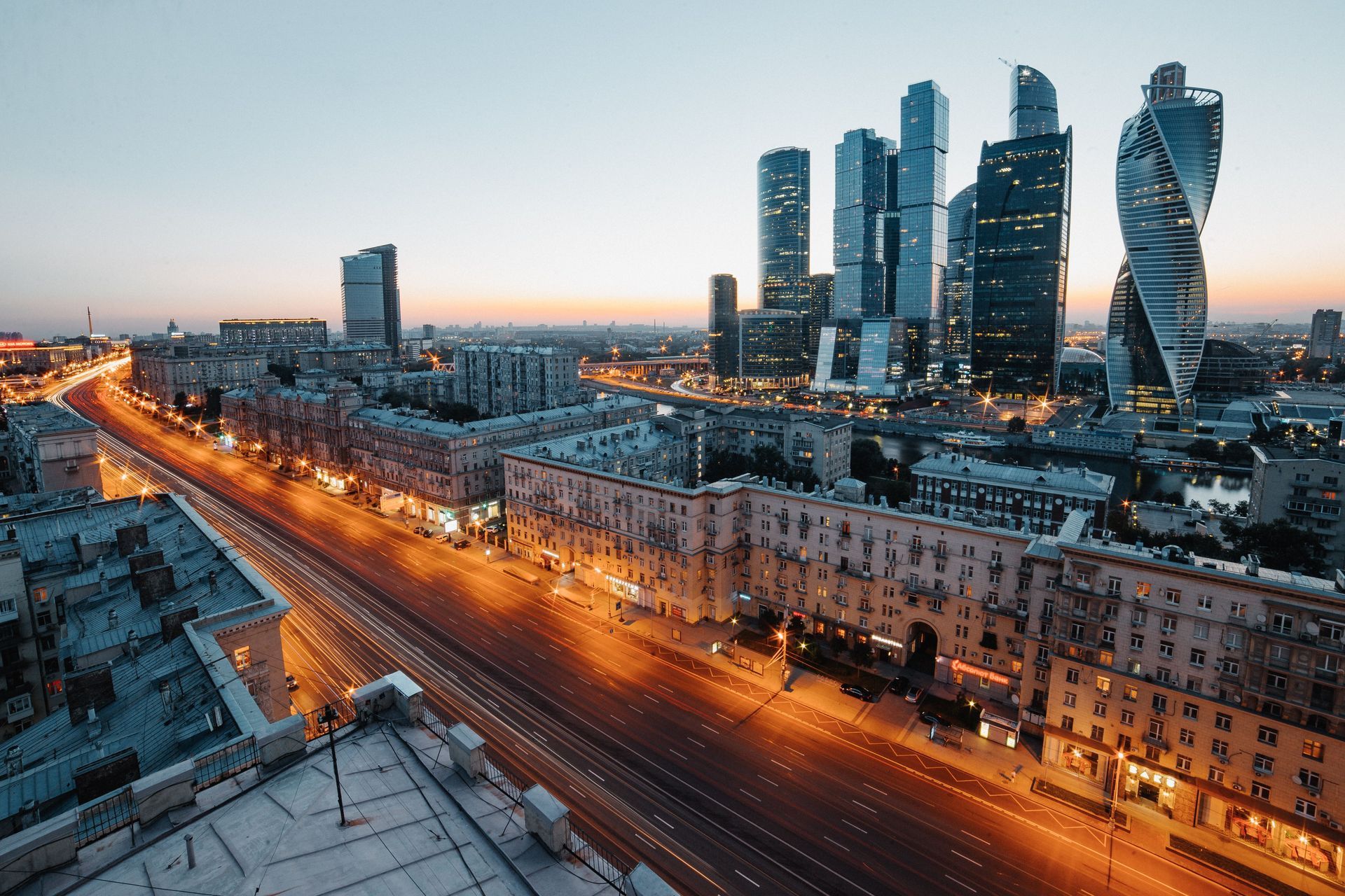 Snowy city skyline at dusk with illuminated highway and modern high-rise towers.