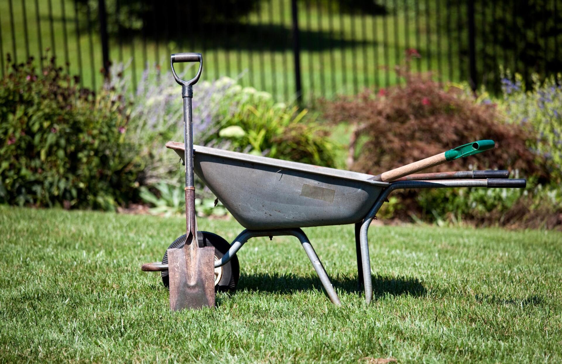Landscaping Services offered by Yorba Landscaping in Yorba Linda. Shows Wheelbarrow with various landscaping tools in freshly mowed grass in front of newly planted flowers and bushes