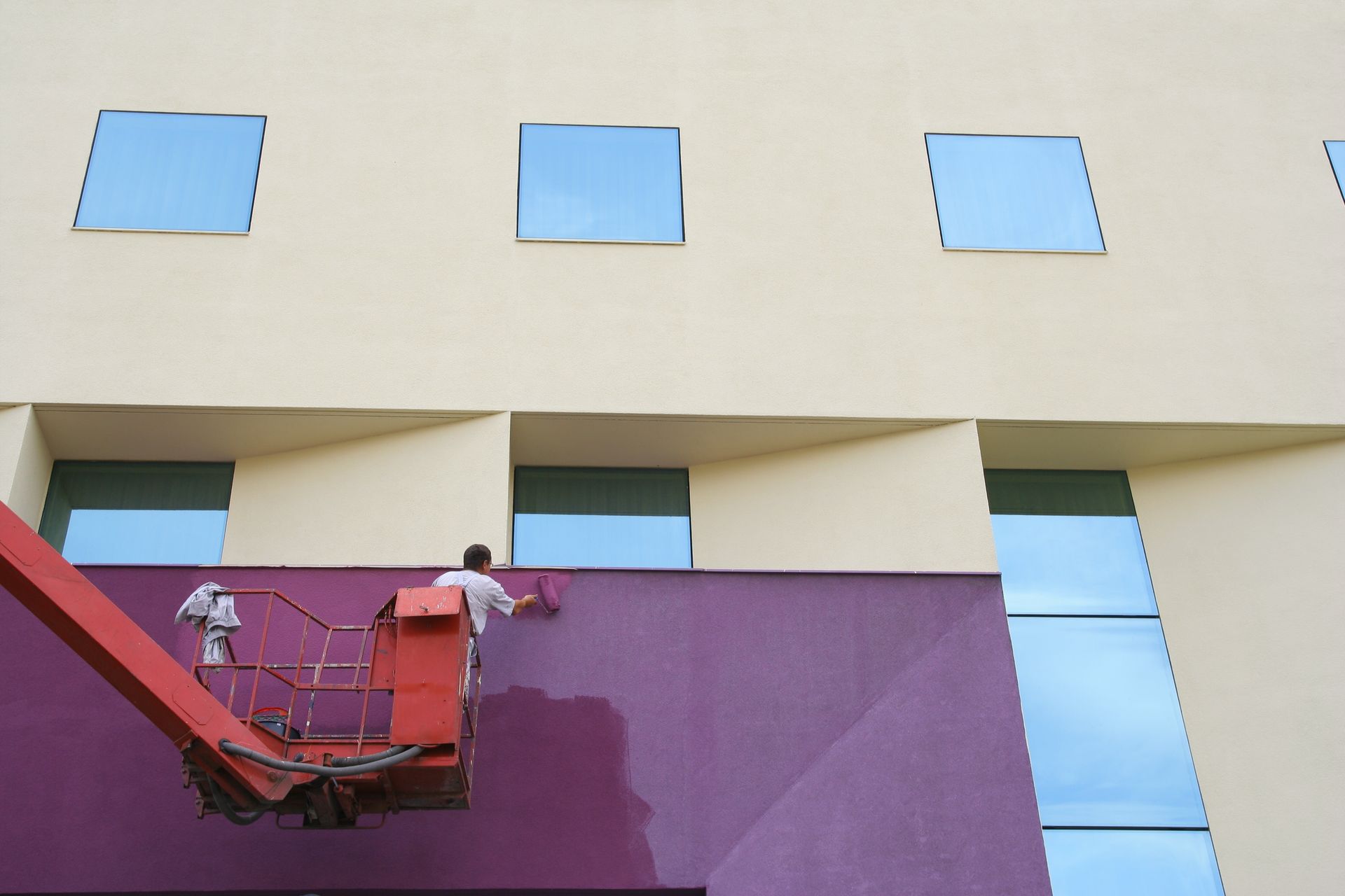 Professional painting contractor applying fresh paint to a commercial building exterior.