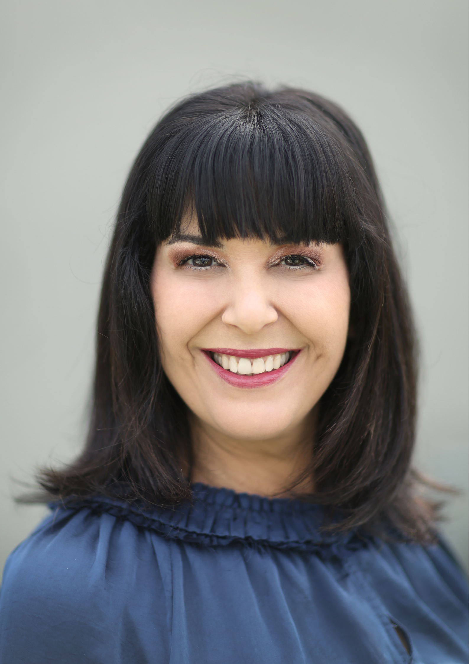 A woman with dark hair and bangs is smiling in a circle