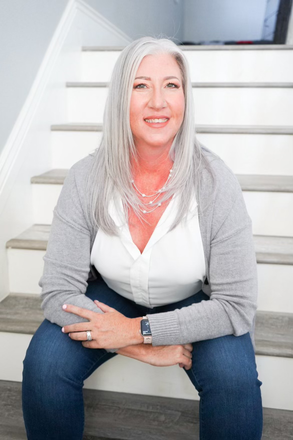 A woman is sitting on a set of stairs with her legs crossed.