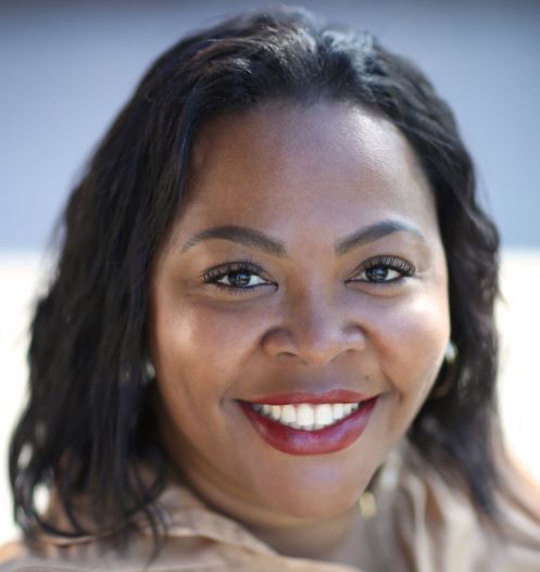 A woman is smiling and wearing red lipstick
