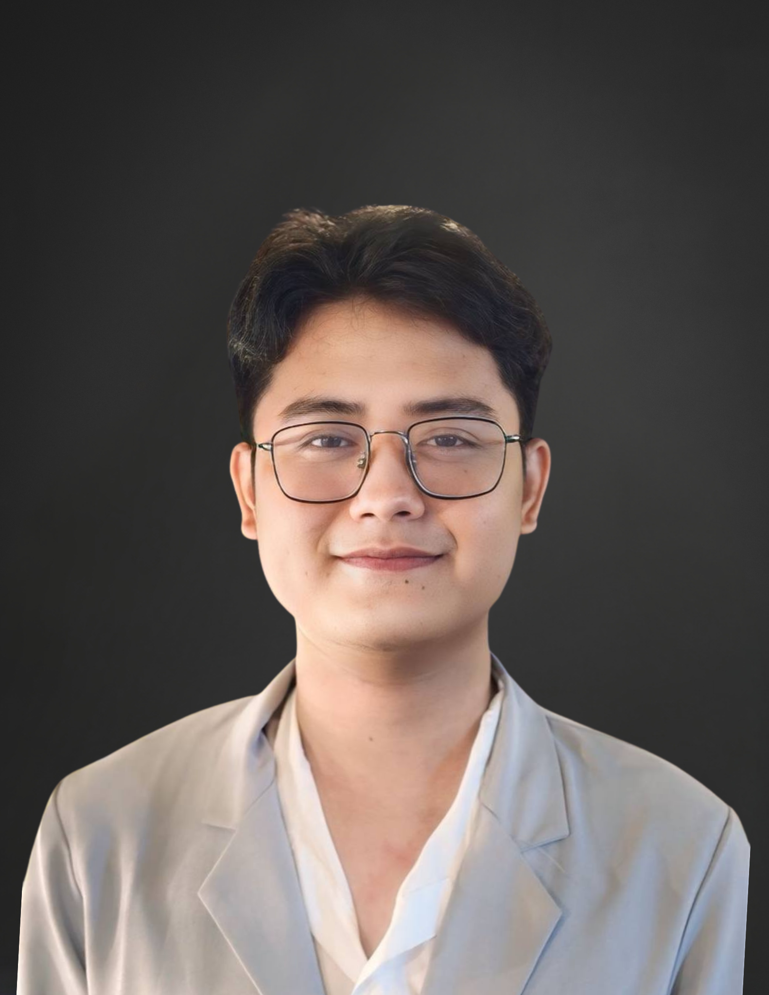 A young man wearing glasses and a suit is smiling for the camera.