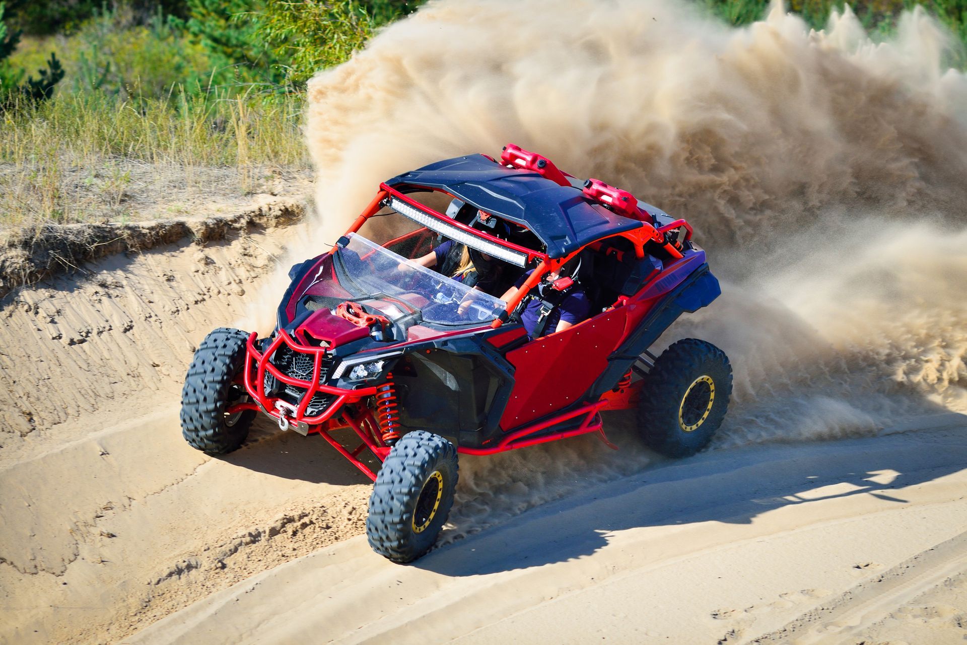 A red atv is driving down a dirt road.
