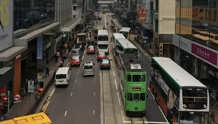 A green double decker bus is driving down a city street.