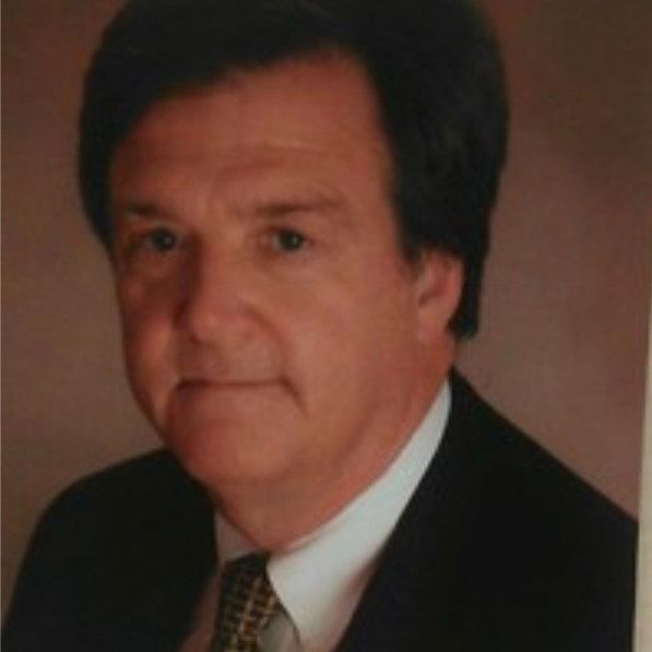 A woman wearing a gray jacket and a white shirt is smiling for the camera.