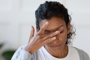 young dark-skinned woman holding her eye in pain