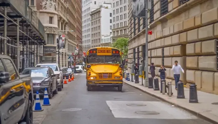 A yellow school bus is driving down a city street.