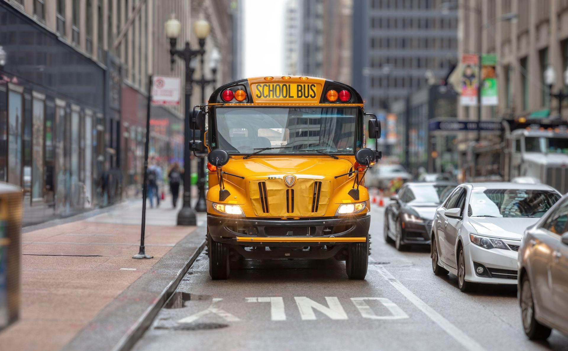 A yellow school bus is driving down a city street.