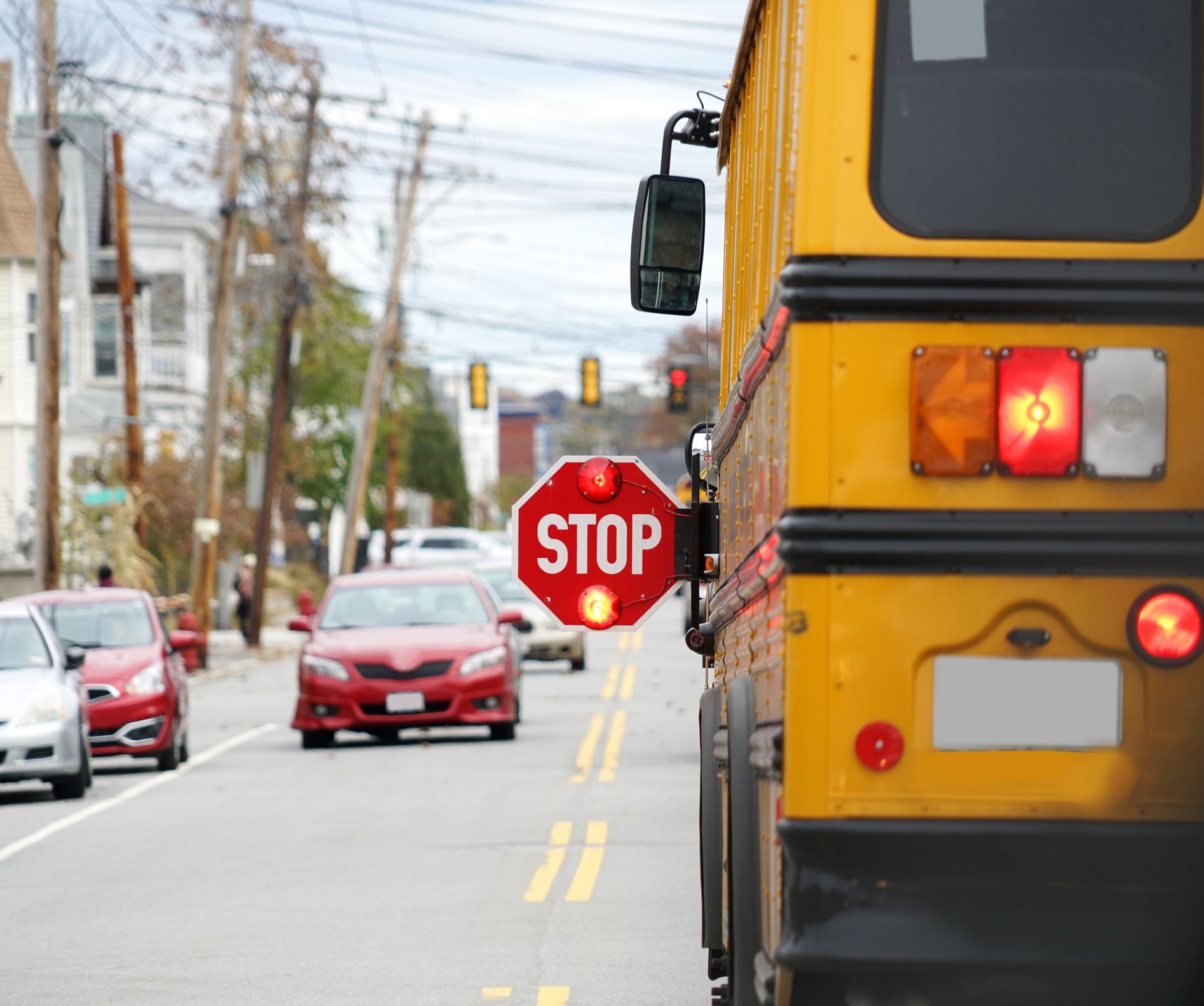 A school bus is driving down a street with a stop sign in front of it.