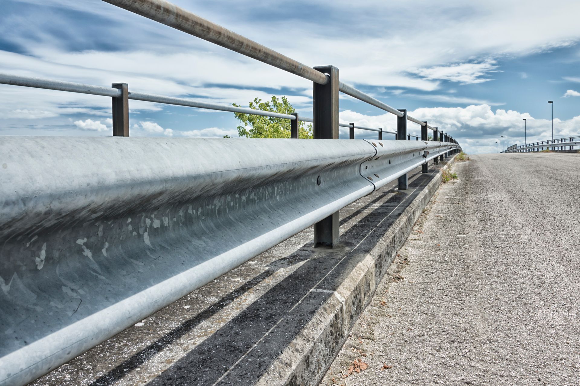 A metal fence along the side of a gravel road.