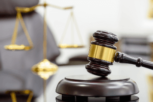 A judge 's gavel is sitting on a table in front of a scale of justice.