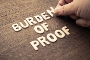 A person is putting the word burden of proof on a wooden table.