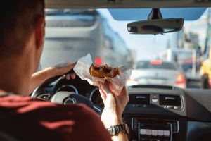 man eating behind the wheel while in traffic