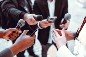 woman speaking to a group of people with microphones
