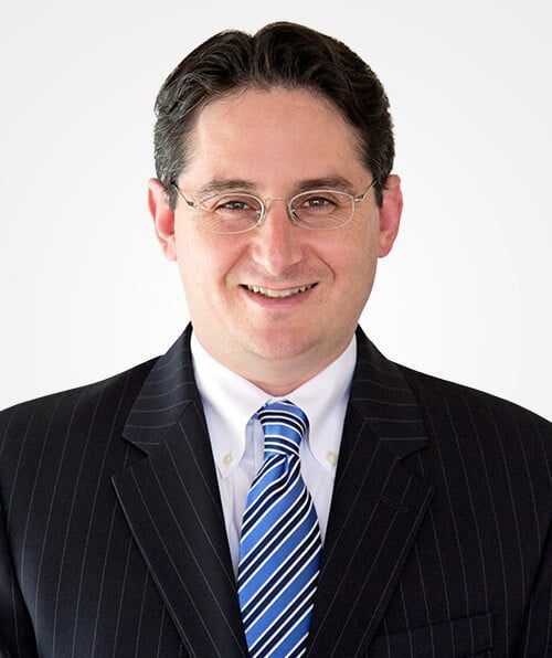 A man in a suit and tie is smiling for the camera