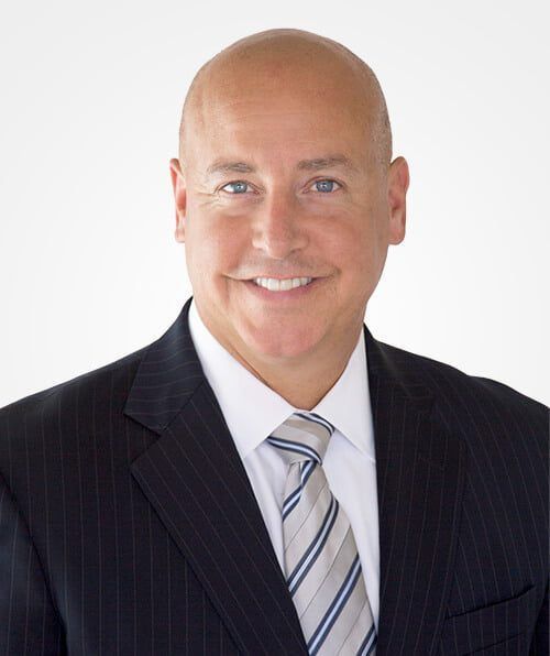 A man in a suit and tie is smiling for the camera